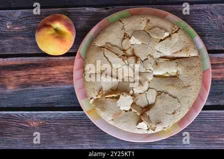 Frisch gebackener hausgemachter charlotte Pie mit Pfirsichen. Kuchen mit knuspriger Kruste, serviert auf rustikalem Holztisch. Saftige Pfirsichfrucht. Draufsicht. Stockfoto