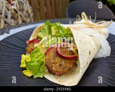 Vegane Falafel-Wrap mit frischem Salat und karamelisierten roten Zwiebeln Stockfoto