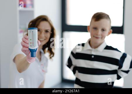 Pädiatrischer Pulmonologe hilft dem Jungen mit Peak Flow Meter. Pulmonologe, Arzt, der auf die Diagnose und Behandlung von Krankheiten spezialisiert ist und Stockfoto