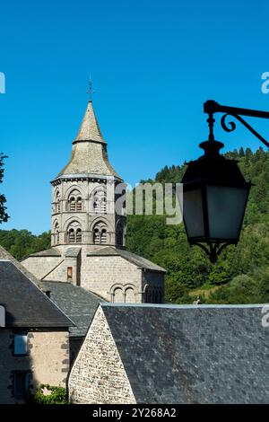 Glockenturm der Basilika Notre-Dame d'Orcival mit romanischer Architektur unter klarem blauen Himmel, Puy de Dome, Auvergne-Rhone-Alpes, Frankreich Stockfoto