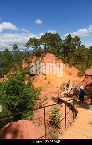 Touristen steigen einen Boardwalk Trail entlang des Sentier des ocres oder Ochre Trail in Roussillon im Luberon Regional Park Vaucluse Provence Frankreich ab Stockfoto