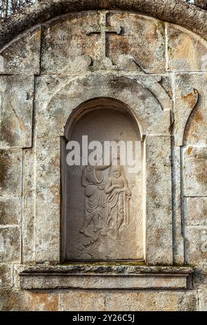 Steinnische mit einem Kreuz und einem Basrelief, das die Taufe Jesu durch Johannes den Täufer darstellt. Bisegna, Provinz L'Aquila, Abruzzen, Italien, Europa Stockfoto