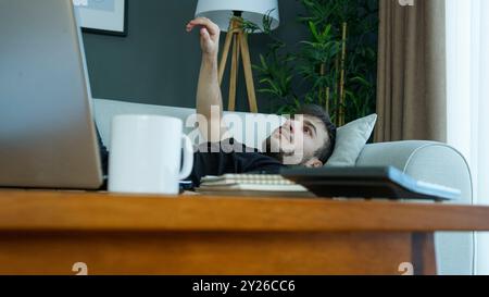 Ein Mann wacht plötzlich aus einem schrecklichen Albtraum auf, liegt mit einem verstörten Ausdruck auf einer Couch. Schock und Verwirrung, die Beunruhigung schlechter Träume. Stockfoto