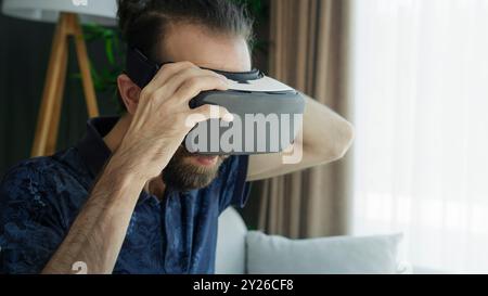 Ein junger Mann mit einem VR-Headset erkundet die Virtual-Reality-Erfahrung. Interaktion mit der virtuellen Umgebung Stockfoto