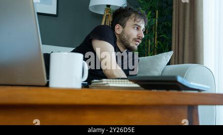 Der Mann wacht plötzlich aus einem schrecklichen Albtraum auf, liegt mit einem verstörten Ausdruck auf einer Couch. Schock und Verwirrung, die Beunruhigung schlechter Träume. Stockfoto