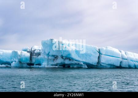 Blau-weiße Eisberge schweben in einem Gletschersee vor dem Hintergrund von Gletschern und schaffen eine ruhige Szene. Unberührtes Jokulsarlon, Island. Stockfoto