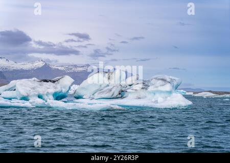 Blau-weiße Eisberge schweben in einem Gletschersee vor dem Hintergrund von Gletschern und schaffen eine ruhige Szene. Unberührtes Jokulsarlon, Island. Stockfoto