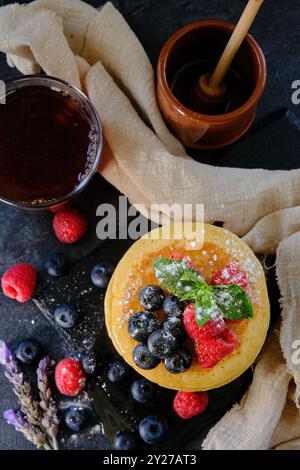 Pfannkuchen mit Beeren und Honig auf dunklem Hintergrund von oben Stockfoto