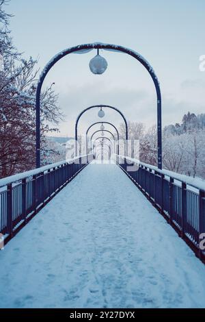 Schneebedeckter Wanderweg Einer Brücke mit Fußabdrücken in der Schneedecke an einem kalten Wintertag Stockfoto