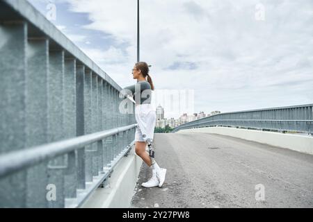 Eine entschlossene junge Frau in Sportbekleidung nimmt an einer malerischen Brücke Fitnessaktivitäten Teil. Stockfoto