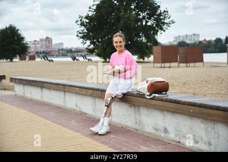 Eine junge Frau mit einer Beinprothese entspannt sich im Freien, liest, während sie den schönen Tag genießt. Stockfoto