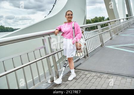 Eine junge Frau mit einer Beinprothese lächelt, die einen aktiven Lebensstil im Freien annimmt. Stockfoto