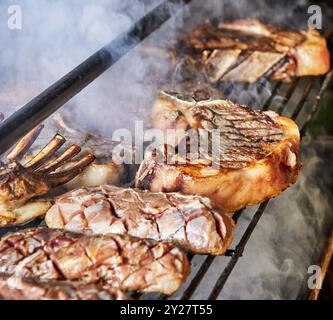 Gegrillte Steaks und Rippchen, die auf dem Grill zubereitet werden Stockfoto