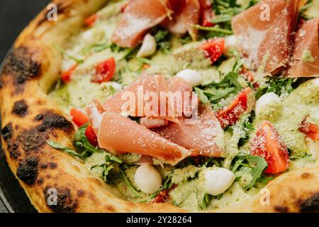 Gourmet-Pizza mit Schinken, Rucola, Mozzarella und frischen Tomaten - perfekte italienische Küche Stockfoto