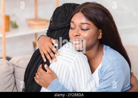 Fake Freundschaft. Gleichgültig Mädchen rollenden Augen umarmt weinend Freund sitzen auf der Couch zu Hause. Selektiver Fokus Stockfoto