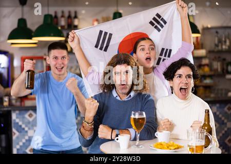 Eine Gruppe von glücklichen Freunden mit der Flagge von Südkorea, die den Sieg ihrer Lieblingsmannschaft in der Bierstube feiern Stockfoto