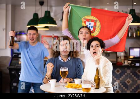 Fans mit der Flagge Portugals feiern den Sieg ihrer Lieblingsmannschaft in der Bierstube Stockfoto