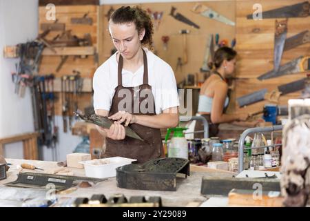 Junger Mann, der interessanterweise größere Schimmelpilze in der Werkstatt sieht Stockfoto