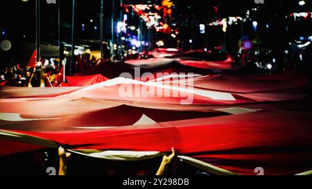 Izmir, Türkei. September 2024. Der Jahrestag der Befreiung von Izmir am 9. September, ein wichtiges Datum im türkischen Unabhängigkeitskrieg. Bei der Veranstaltung, bei der der 102. Jahrestag der Befreiung Izmirs von der feindlichen Besatzung gefeiert wurde, wurde eine 350 Meter hohe türkische Flagge von den Menschen getragen, die an der Fackelprozession teilnahmen. Quelle: İdil Toffolo/Alamy Live News Stockfoto