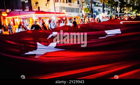 Izmir, Türkei. September 2024. Der Jahrestag der Befreiung von Izmir am 9. September, ein wichtiges Datum im türkischen Unabhängigkeitskrieg. Bei der Veranstaltung, bei der der 102. Jahrestag der Befreiung Izmirs von der feindlichen Besatzung gefeiert wurde, wurde eine 350 Meter hohe türkische Flagge von den Menschen getragen, die an der Fackelprozession teilnahmen. Quelle: İdil Toffolo/Alamy Live News Stockfoto