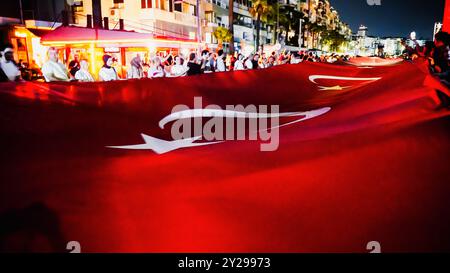 Izmir, Türkei. September 2024. Der Jahrestag der Befreiung von Izmir am 9. September, ein wichtiges Datum im türkischen Unabhängigkeitskrieg. Bei der Veranstaltung, bei der der 102. Jahrestag der Befreiung Izmirs von der feindlichen Besatzung gefeiert wurde, wurde eine 350 Meter hohe türkische Flagge von den Menschen getragen, die an der Fackelprozession teilnahmen. Quelle: İdil Toffolo/Alamy Live News Stockfoto