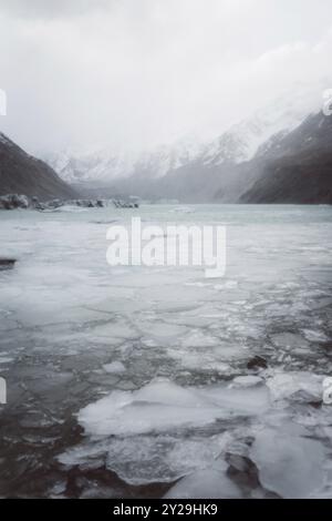 Gefrorener See mit Eisschollen, umgeben von hohen, schneebedeckten Bergen im Winter, Hooker Valley Track, Neuseeland, Ozeanien Stockfoto