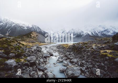 Der Fluss fließt durch eine felsige, verschneite Berglandschaft, Hooker Valley Track, Neuseeland, Ozeanien Stockfoto