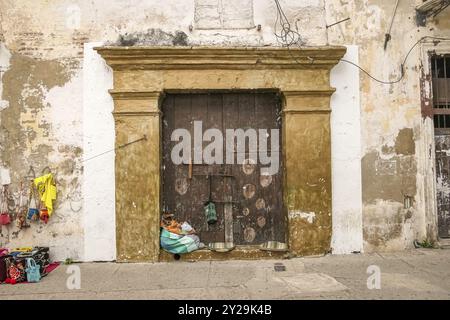 Alte Kirchentür mit bunten Verkaufswaren eines Straßenverkäufers, Cartagena, Kolumbien, Südamerika Stockfoto