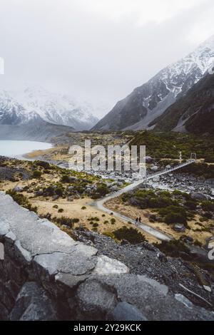 Hängebrücke über einen Fluss in einer bergigen, schneebedeckten Landschaft mit nebeliger Atmosphäre, Hooker Valley Track, Neuseeland, Ozeanien Stockfoto