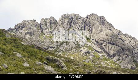 Malerische, zerklüftete Granitberge der Serra da Mantiqueira (Mantiqueira Gebirgskette) mit grasbedeckten Teilen vor hellem Hintergrund, obere Itatiaia, Stockfoto