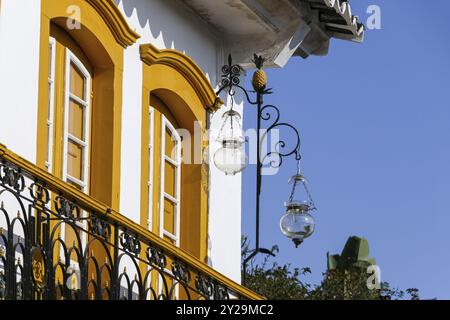 Nahaufnahme eines kunstvollen Kolonialhauses mit zwei gelben, hohen Glastüren, Metall Balustrade und einer Laterne in der Sonne, historische Stadt Paraty Stockfoto