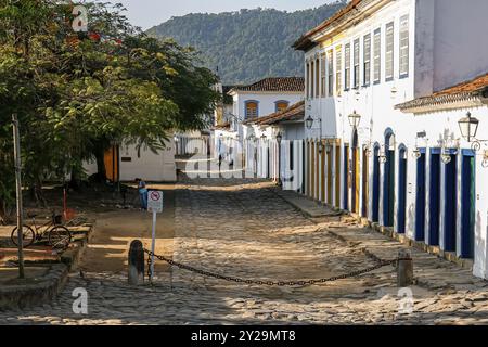 Typische Kopfsteinpflasterstraße mit Kolonialgebäuden an einem Platz mit Bäumen im Nachmittagslicht in der historischen Stadt Paraty, Brasilien, Südamerika Stockfoto