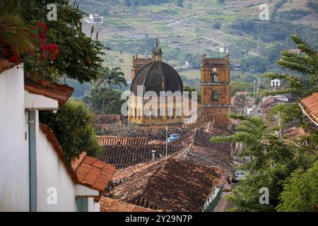 Blick von der Spitze der Stadt über Dächer auf das historische Zentrum von Barichara, Kolumbien mit der Kathedrale der makellosen Konzeption und der grünen Landschaft Stockfoto