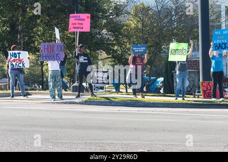 Suwanee, GA / USA - 7. September 2024: Freiwillige demokratischer Parteien ermutigen vorbeifahrende Fahrzeuge, sich bei einer lokalen Veranstaltung von Honk for Harris die Hörner zu blasen. Stockfoto