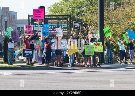 Suwanee, GA / USA - 7. September 2024: Freiwillige demokratischer Parteien ermutigen vorbeifahrende Fahrzeuge, sich bei einer lokalen Veranstaltung von Honk for Harris die Hörner zu blasen. Stockfoto