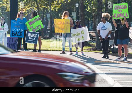 Suwanee, GA / USA - 7. September 2024: Demokratische Aktivisten ermutigen Fahrzeuge, sich die Hörner zu blasen, während sie bei einer Veranstaltung von Honk for Harris Schilder hochhalten. Stockfoto