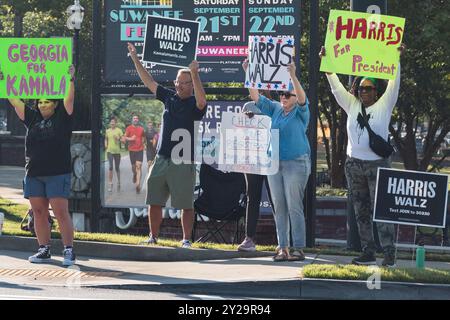 Suwanee, GA / USA - 7. September 2024: Demokratische Aktivisten ermutigen Fahrzeuge, sich die Hörner zu blasen, während sie bei einer Veranstaltung von Honk for Harris Schilder hochhalten. Stockfoto