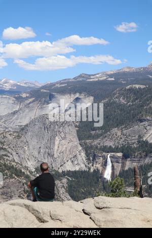 Mann am Rande einer Klippe mit Blick auf den Wasserfall im Yosemite National Park, Kalifornien Stockfoto