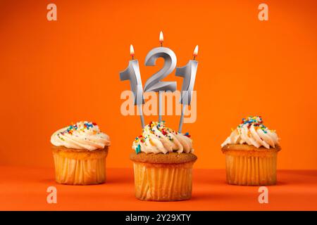 Kerze Nummer 121 - Feier mit Geburtstagskuchen auf orangem Hintergrund Stockfoto