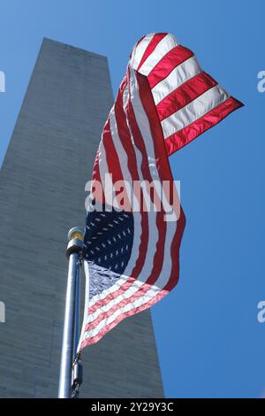 Die US-Flagge weht im Wind am Washington Monument in D.C. mit blauem Himmel Stockfoto