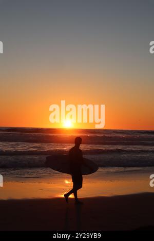 Surfer Silhouette spazieren am Strand bei orangefarbenem Sonnenuntergang am Pacific Beach, San Diego, Kalifornien Stockfoto