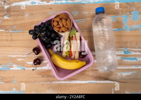 Präsentation des Mittagessens in der Schule. Draufsicht mit einer umweltfreundlichen Lunchbox gefüllt mit nahrhaften Lebensmitteln, Proteinen, Früchten und Körnern Stockfoto