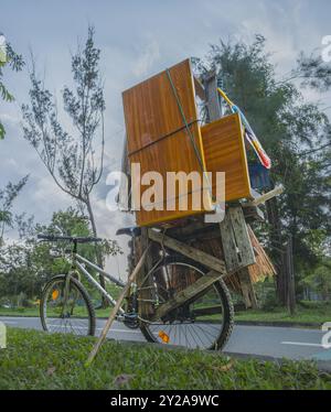 Balikpapan, Indonesien - 9. August 2024. Das alte Fahrrad trägt eine Menge Möbel und Haushaltsreinigungsbedarf. Stockfoto