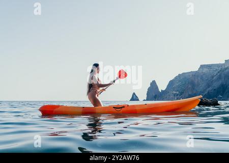 Frau Kajak Meer Paddle Küste - Junge Frau Kajak auf dem Meer mit Klippen im Hintergrund an einem sonnigen Tag. Stockfoto