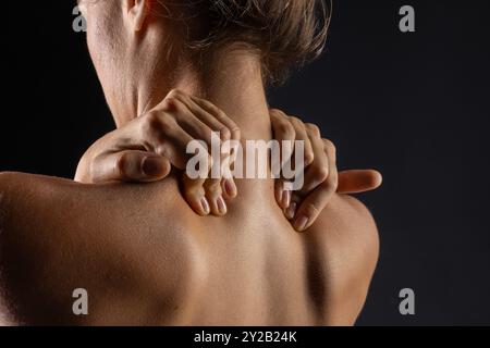 Frau massiert den Hals in Nahaufnahme, Konzept von Nackenschmerzen mit Osteochondrose-Protrusion und Hernie in der Halswirbelsäule, Stockfoto