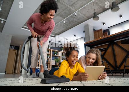 Porträt einer glücklichen Mutter im Haushalt, während Kinder zu Hause Spaß mit Gadgets haben Stockfoto