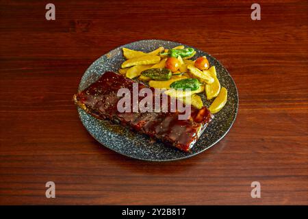Ein typisch amerikanisches Rezept für Grillrippchen mit einer hellen Sauce und einer Beilage aus Kartoffeln und grünem Paprika Stockfoto