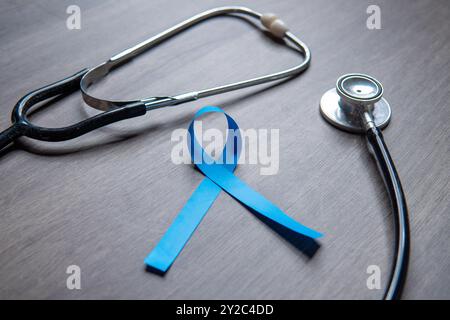 Ein blaues Band und ein Stethoskop auf einer Holzoberfläche. Männer Gesundheit, Prostatakrebs Bewusstsein Konzept. Stockfoto