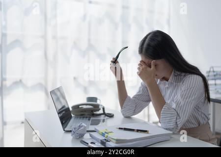 Geschäftsfrau plant eine Finanzprüfung, prüft Dokumente, während sie gegen das Burnout-Syndrom kämpft Stockfoto