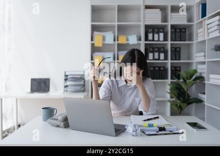 Geschäftsfrau plant eine Finanzprüfung, prüft Dokumente, während sie gegen das Burnout-Syndrom kämpft Stockfoto